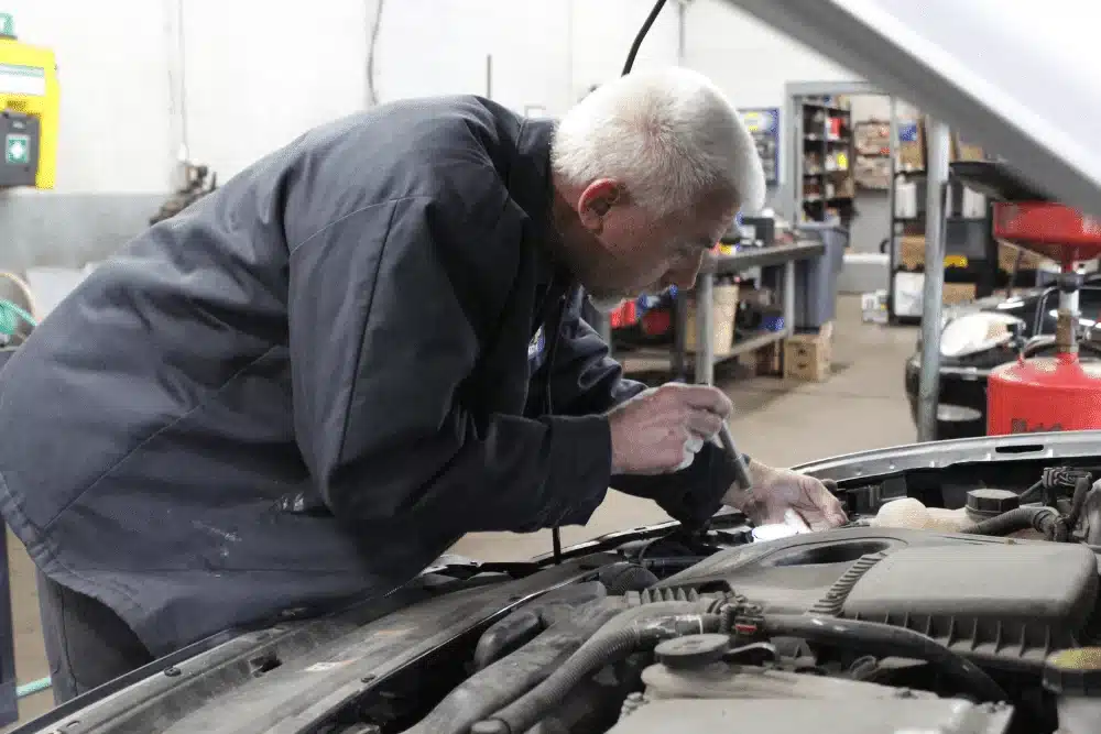 car care tips, auto repair in Lansing, MI at Jerry's Automotive. An image of automotive technician inspecting a vehicle engine bay with a flashlight, ensuring precise diagnostics and maintenance.