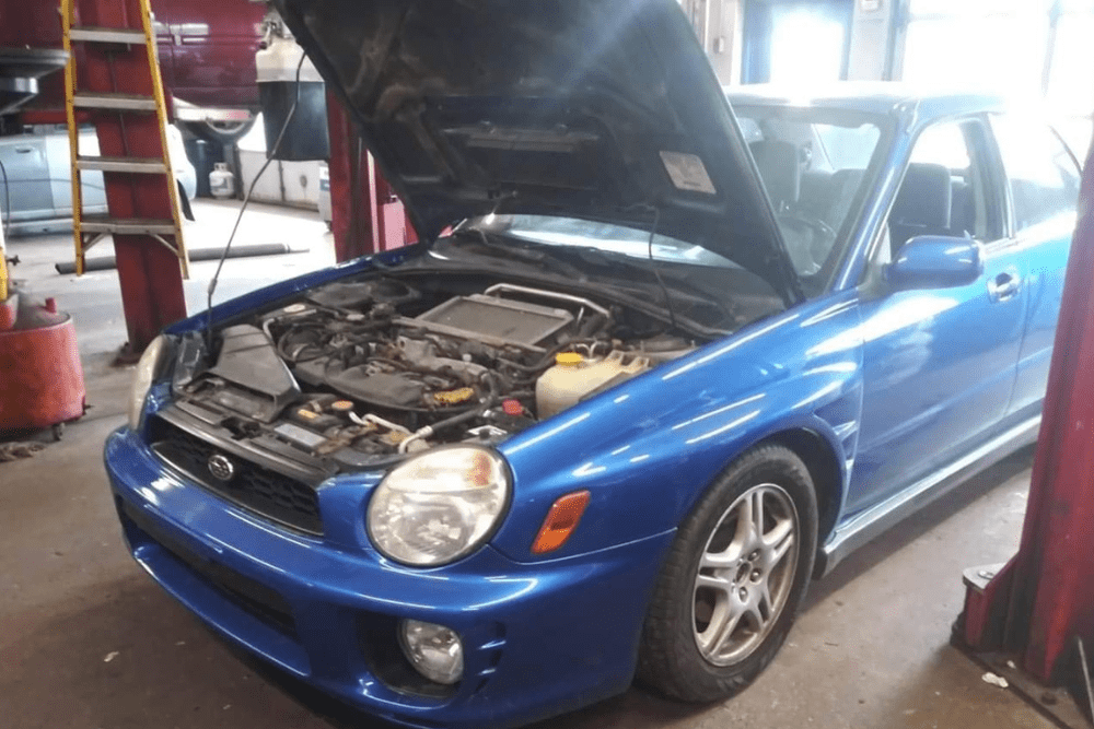 Subaru WRX undergoing car maintenance & services at Jerry’s Automotive in Lansing, MI. The hood is open, exposing the turbocharged engine in a service bay.
