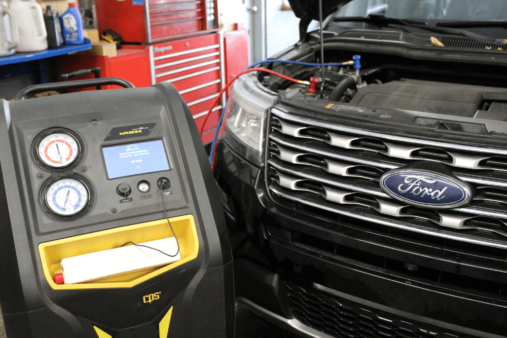 Auto A/C Repair in Lansing, MI by Jerry's Automotive. Image shows a Ford vehicle undergoing air conditioning service with a CPS A/C machine connected under the hood.