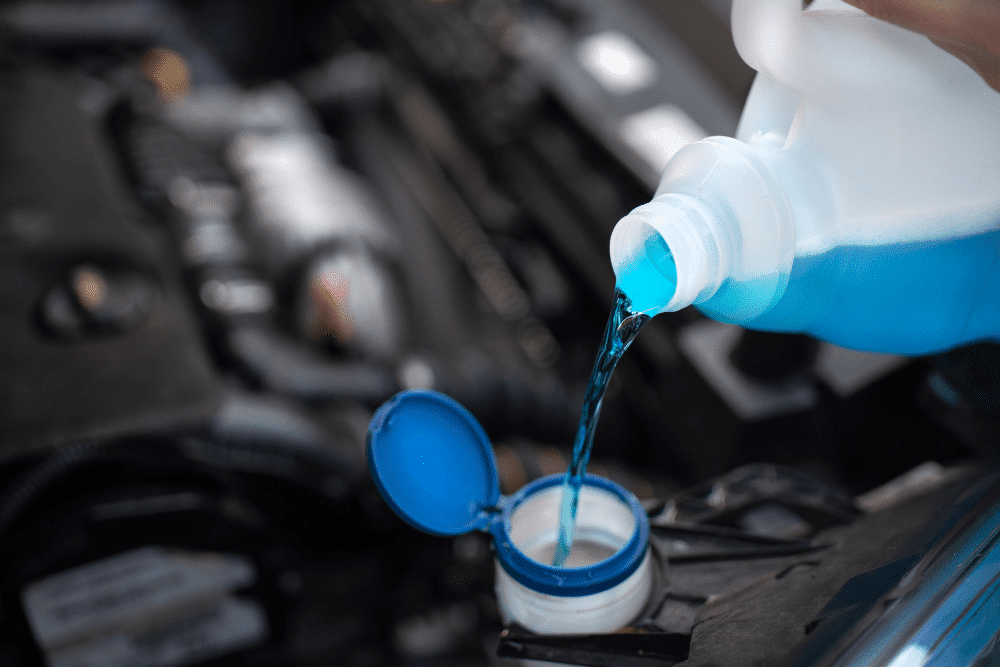 Fluid service, auto repair in Lansing, MI by Jerry’s Automotive. Image of coolant being poured into a vehicle’s reservoir under the hood. Highlighting Jerry’s Automotive’s commitment to proper engine temperature control and reliable vehicle performance.