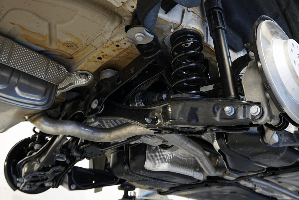 Suspension repair in Lansing, MI, at Jerry’s Automotive. Image of vehicle undercarriage with coil spring, control arm, and shock components, emphasizing safe handling and ride stability.