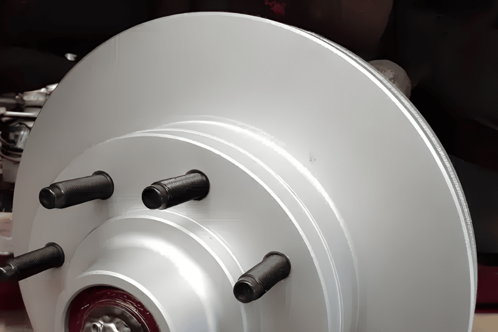 Brake Repair in Lansing, MI At Jerry's Automotive. Close-up of a new coated brake rotor with wheel studs mounted on a vehicle