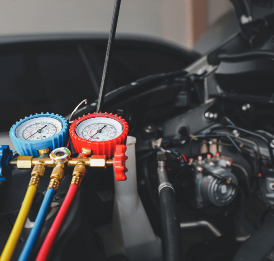 car a/c problems, auto repair in Lansing, MI at Jerry's Automotive. Close-up of an automotive A/C manifold gauge set connected under the hood.