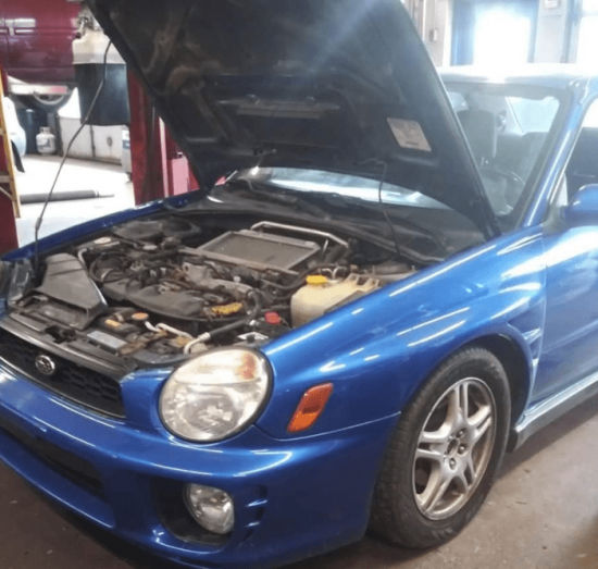 Subaru WRX undergoing car maintenance & services at Jerry’s Automotive in Lansing, MI. The hood is open, exposing the turbocharged engine in a service bay.